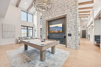 A pool table is in the middle of a room with a stone wall and a painting hanging above it.at The Garrison Luxury Apartment Homes, Fountain